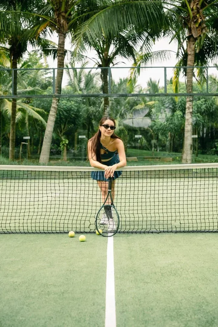 Player resting a hand on the net of an outdoor court between games