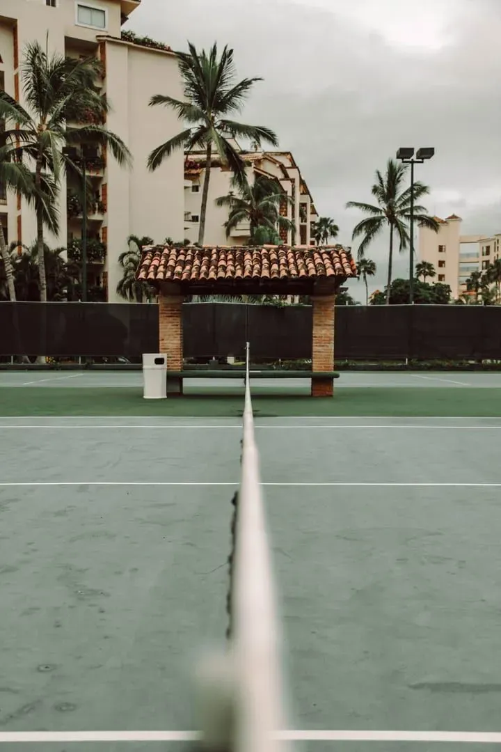 Tropical resort tennis court with a shaded shed at courtside