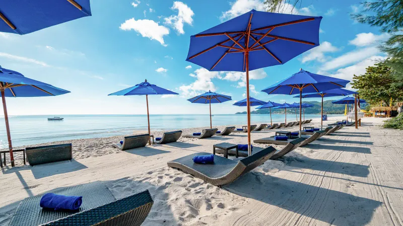 Ombrelloni blu e lettini sulla sabbia bianca della spiaggia di Chaweng davanti all'OZO Chaweng Samui
