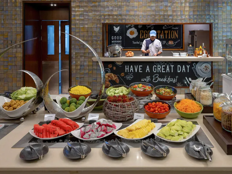 Esposizione di frutta al buffet della colazione dell'OZO Chaweng Samui con uno chef alla postazione dal vivo