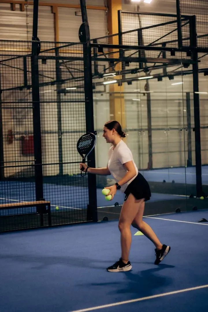 Player holding a padel racket and ball courtside before a match on Koh Samui-style covered courts