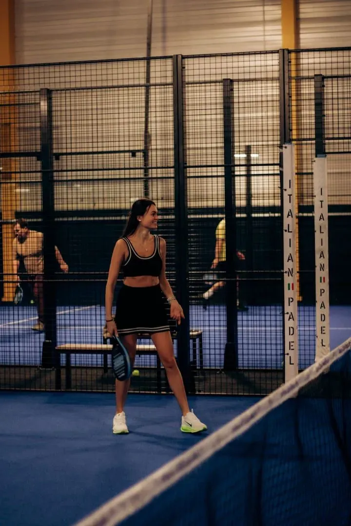 Padel player in sports attire positioned for a return on an indoor court