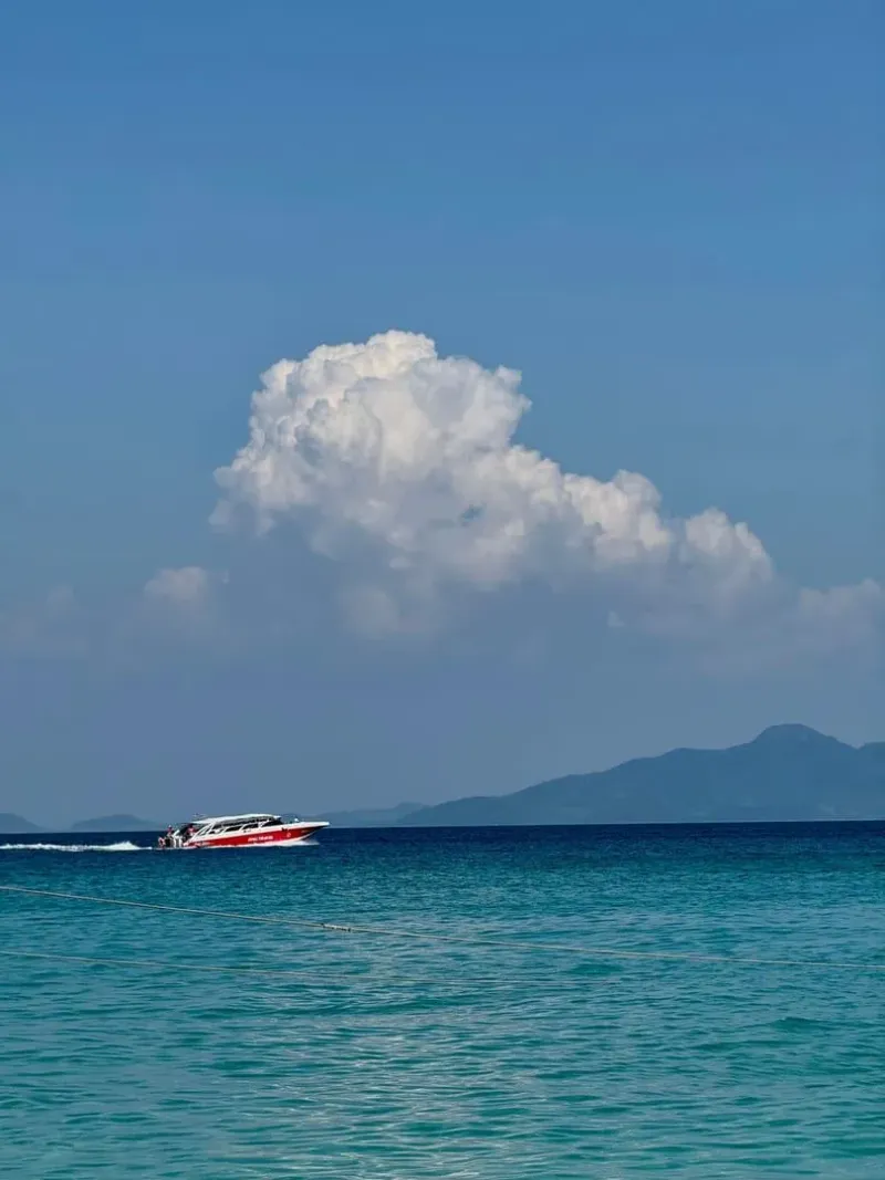 Speedboat cruising turquoise waters near Phuket under a bright blue sky