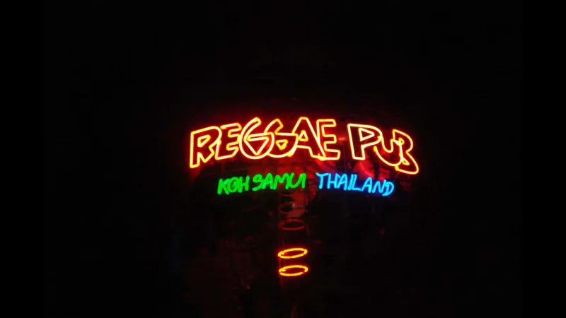 Reggae Pub's neon sign reading 'Reggae Pub, Koh Samui, Thailand' lit up at night