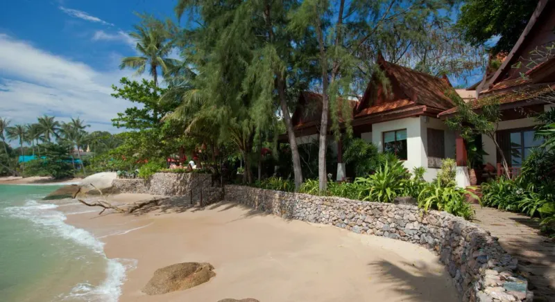 Baia di sabbia con rocce e una villa con tetto di paglia al Rocky's Boutique Resort a Koh Samui
