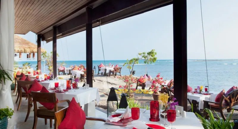 Tavoli per la cena in spiaggia con tovaglie rosse e candele vicino all'acqua al Rocky's Boutique Resort
