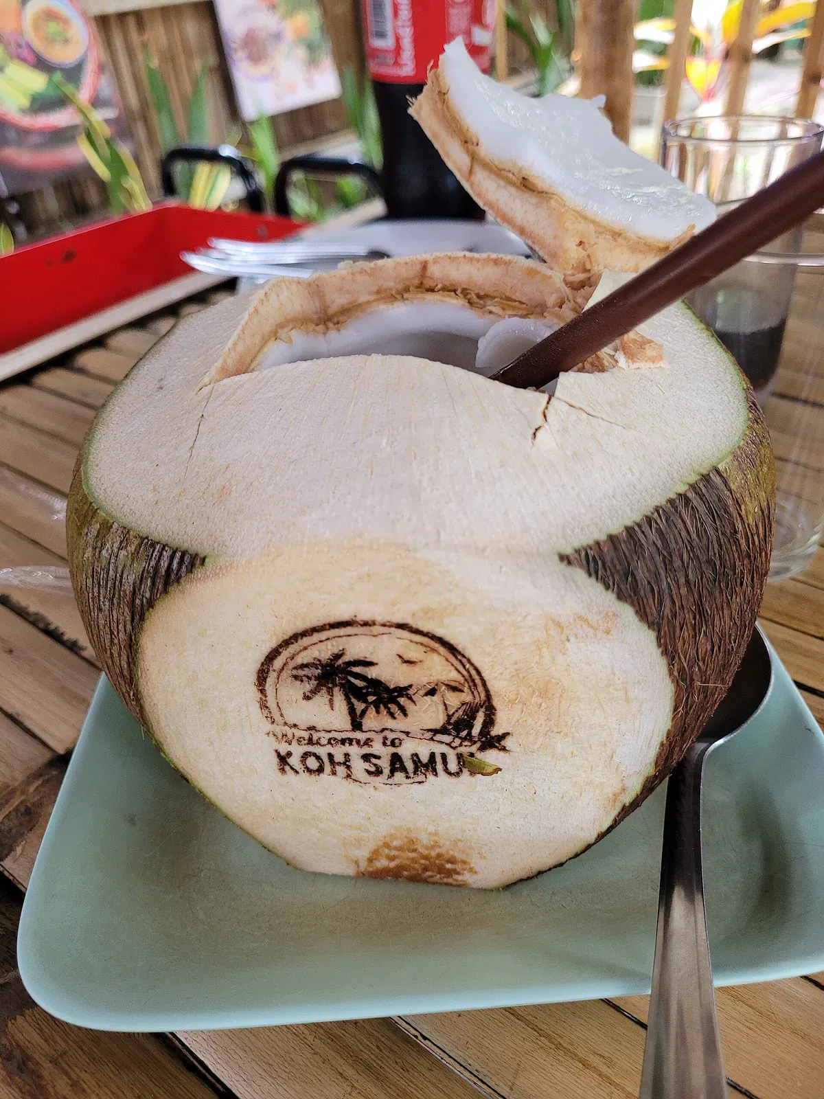 Fresh coconut drink with a Welcome to Koh Samui design carved into the shell