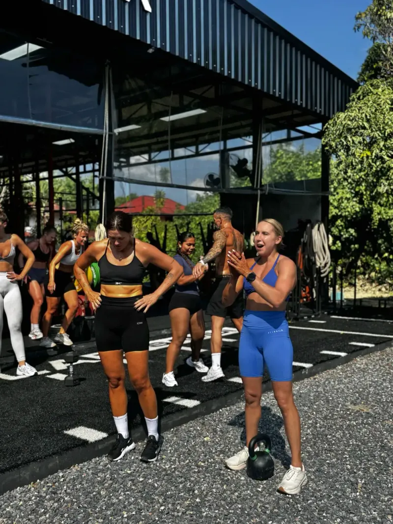 A coached group workout on a turf floor in an open-sided training space