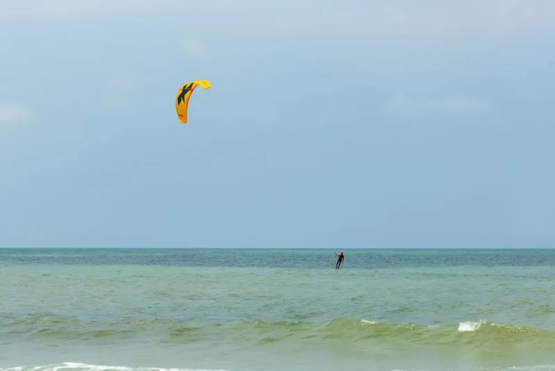 Kitesurfer gliding across open water in Thailand's Gulf wind season