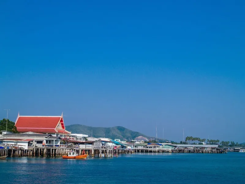 Red-roofed coastal building and boats in a harbor near a Thai fishing village