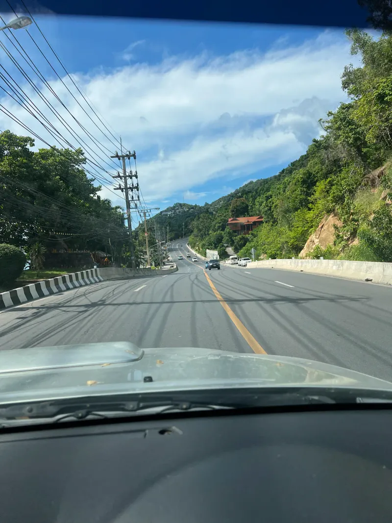 車、トラック、スクーターが走る、タイの島の片側1車線の坂道