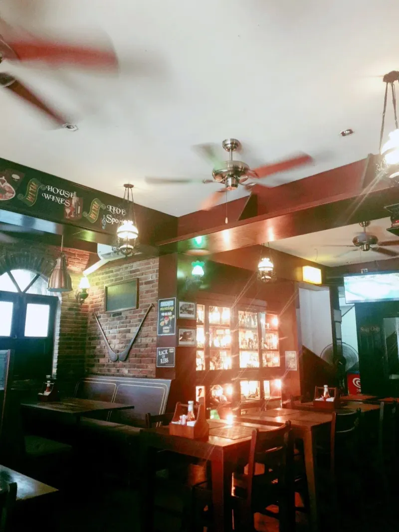 An Irish-style pub interior with brick walls, ceiling fans and framed photos on the wall