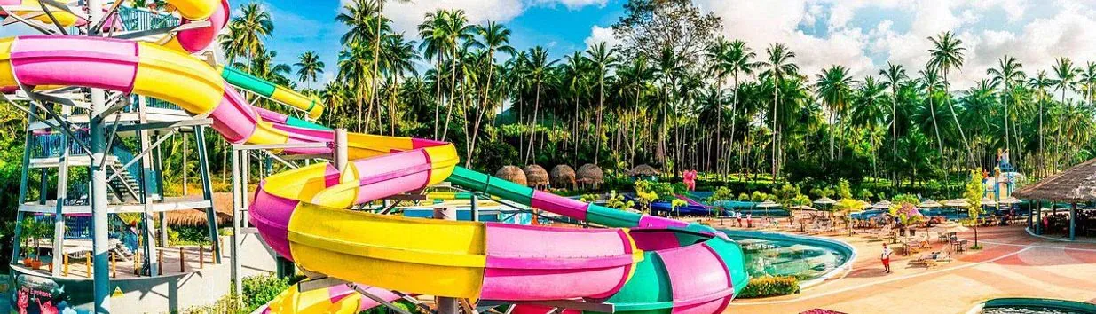 Pink, yellow and green spiral waterslides towering over palm trees at Samui Water Park, Maenam