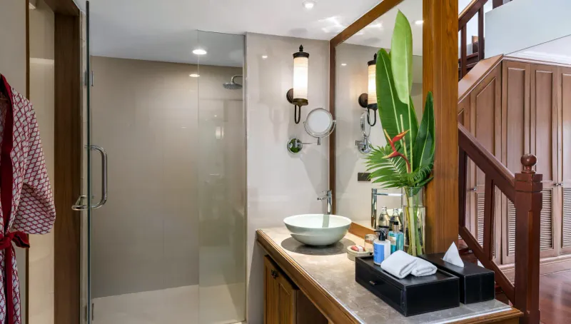 Salle de bains avec douche en verre, plan en pierre et vasque posée dans une chambre de Santiburi Koh Samui
