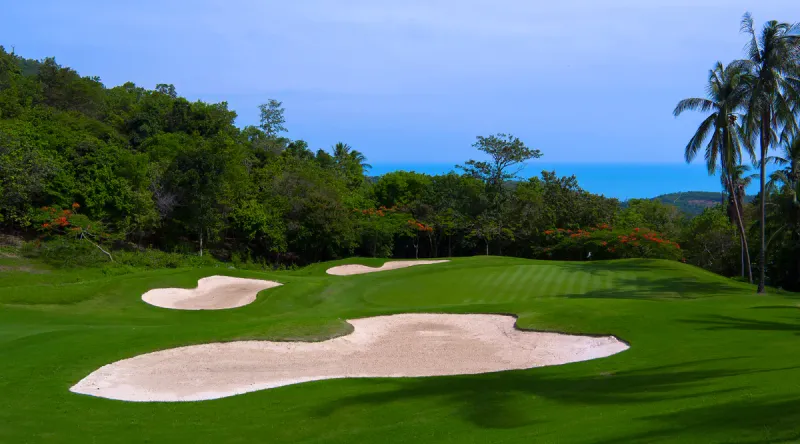 A green and fairway at Santiburi Samui Country Club with hillside jungle framing the hole