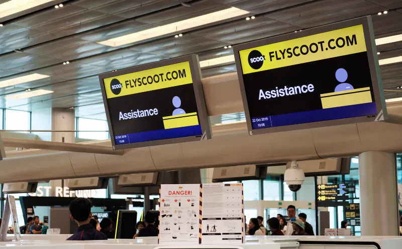 Banco assistenza Scoot con insegne gialle flyscoot.com in un terminal dell'aeroporto Changi di Singapore
