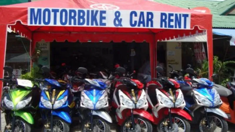 タイの道路沿いにあるバイクと車のレンタル店で、屋根の下に並ぶスクーター
