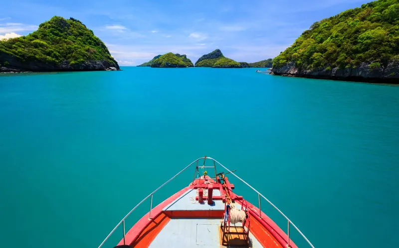 水面の向こうに、「Welcome to Koh Samui」の看板と森の丘が見える、青い屋根のフェリー桟橋