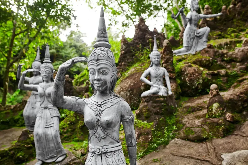 Reihe steinerner Geister auf bemoosten Felsen im Secret Buddha Garden