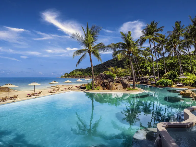 Bordo della piscina a sfioro dello Sheraton Samui Resort accanto alla spiaggia di sabbia bianca, con ombrelloni e palme