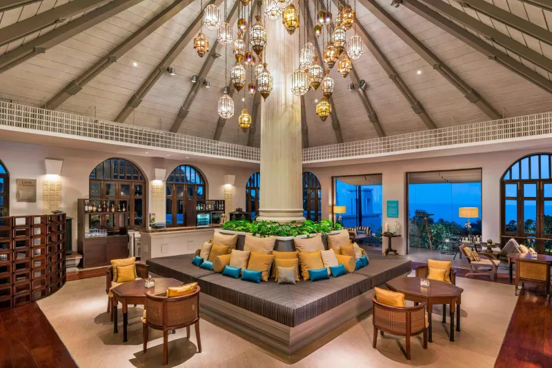 Lounge della lobby con una colonna centrale, lanterne di ottone e un divano circolare allo Sheraton Samui Resort