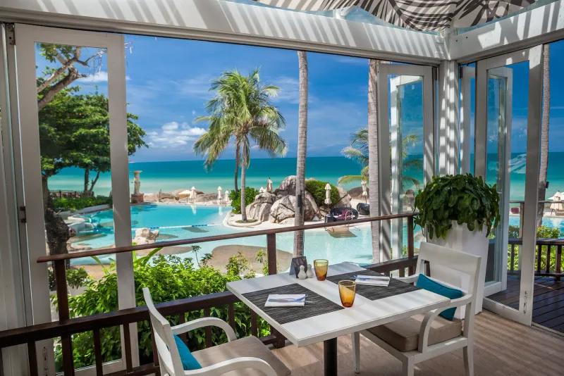Tavolo per due in un ristorante aperto sulla piscina e sul mare allo Sheraton Samui Resort