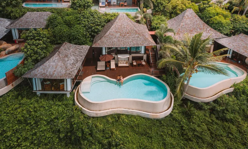 Veduta aerea di una villa con piscina privata a forma di arachide e solarium circondati dalla giungla verde