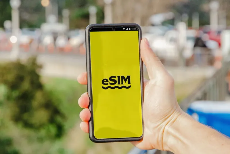 Traveler viewing an eSIM screen on a smartphone against an outdoor backdrop