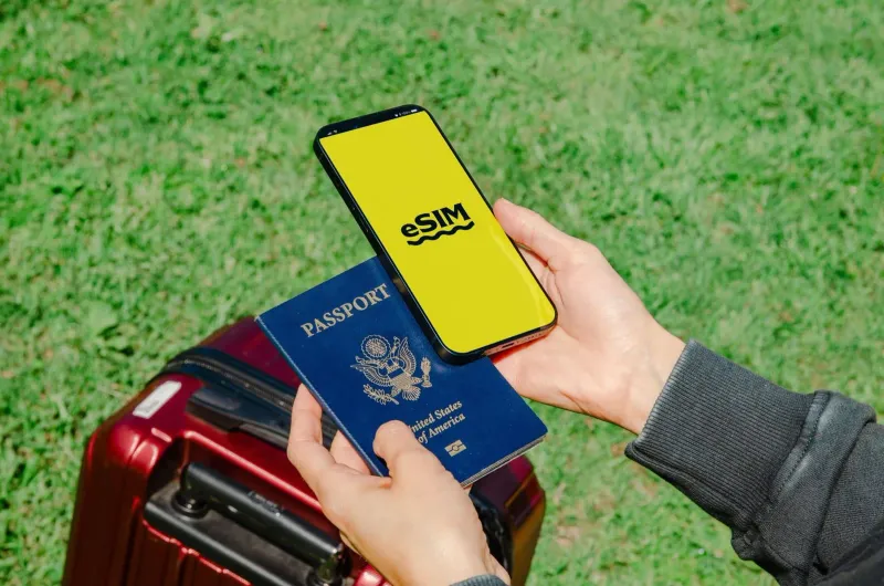 タイ旅行の前に、パスポートと荷物のそばでeSIMの画面を表示したスマートフォンを持つ旅行者