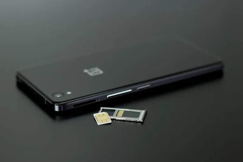 Close-up of a smartphone with SIM card and memory card on a dark table