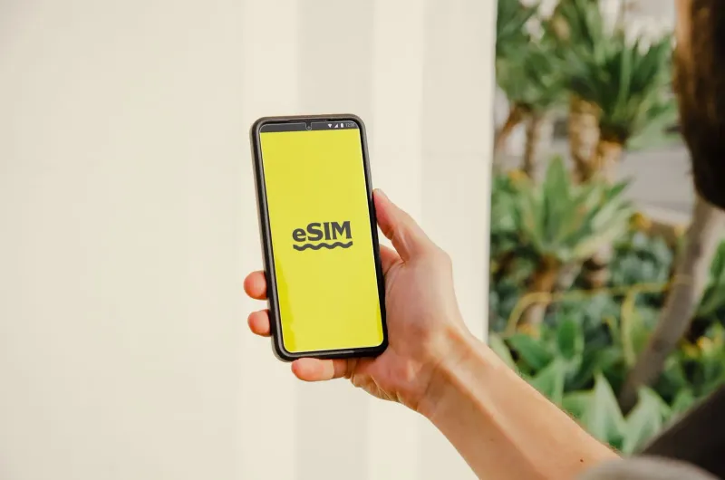 Person holding a smartphone showing an eSIM activation logo outdoors