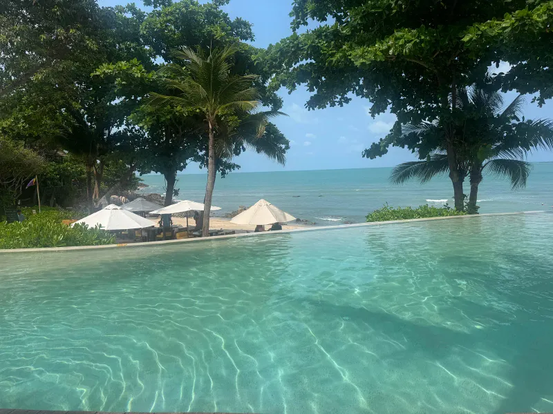 Bordo della piscina a sfioro del Six Senses Samui con vista su palme, ombrelloni da spiaggia e mare