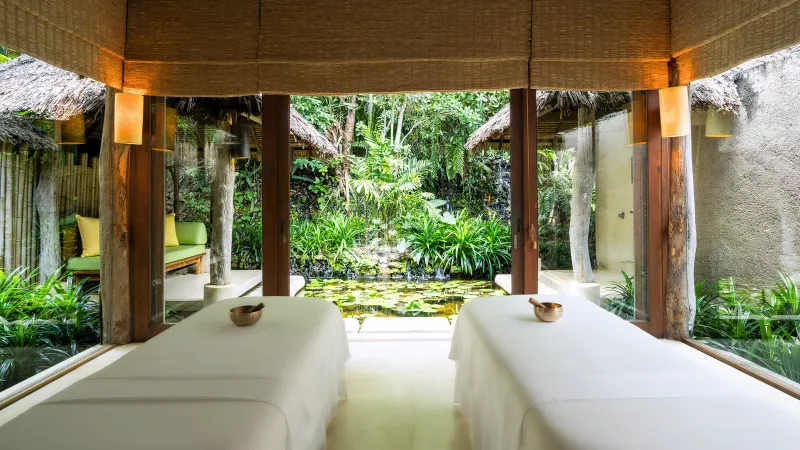 Sala trattamenti per coppie della spa del Six Senses Samui, con due lettini da massaggio che guardano uno stagno nel giardino
