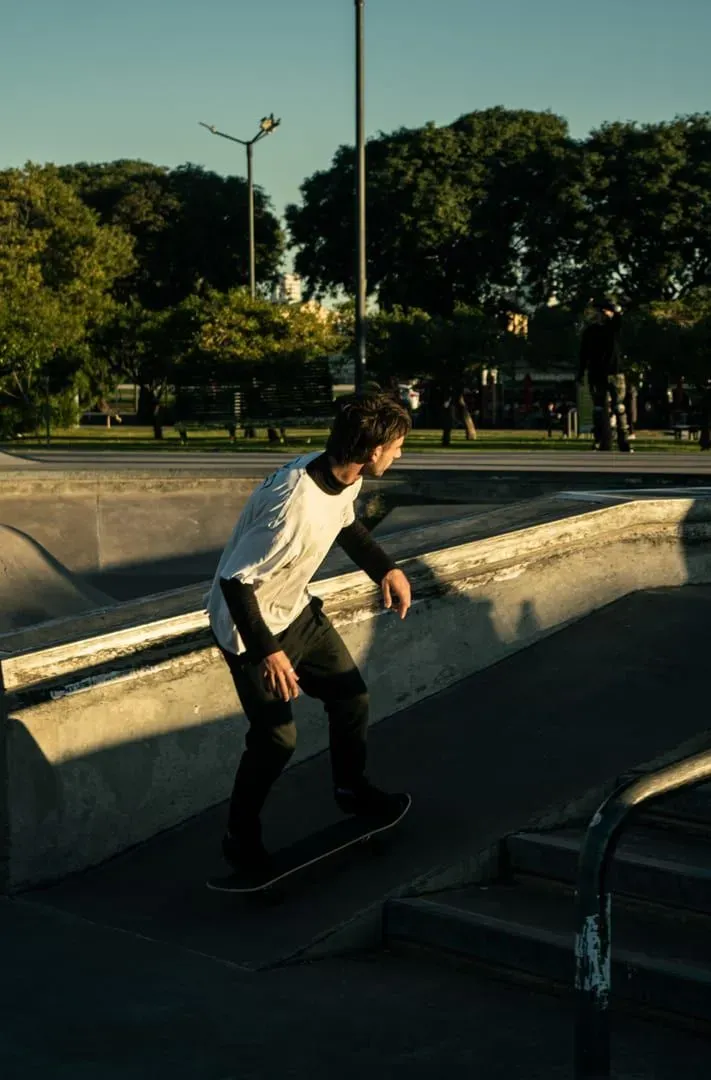 Skateboarder riding an urban skatepark ramp at sunset