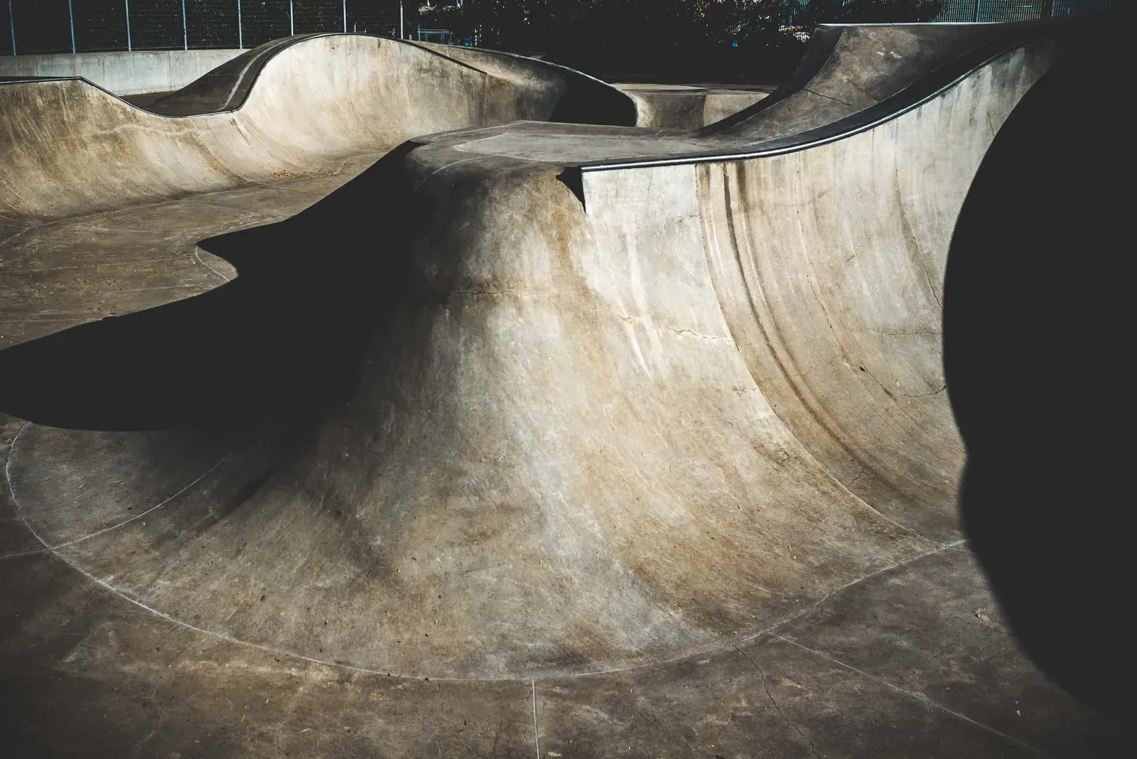 Empty concrete skatepark with strong shadows in bright daylight