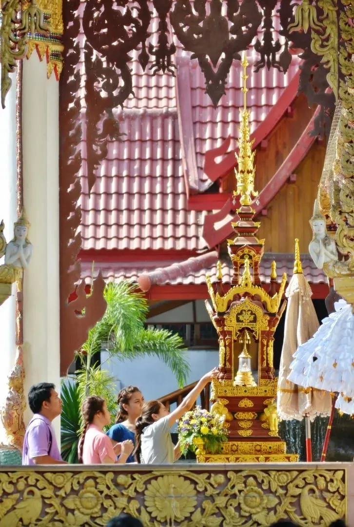 Thai devotee pouring water over a Buddha relic at a temple shrine during the Songkran holiday