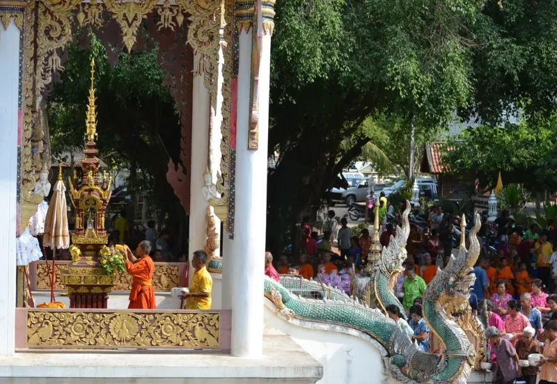 Temple courtyard scene of water being sprinkled on a Buddha statue during Songkran in Thailand