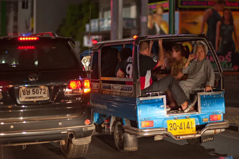Camionnette songthaew bleue pleine de passagers dans la circulation nocturne d'une rue thaïlandaise