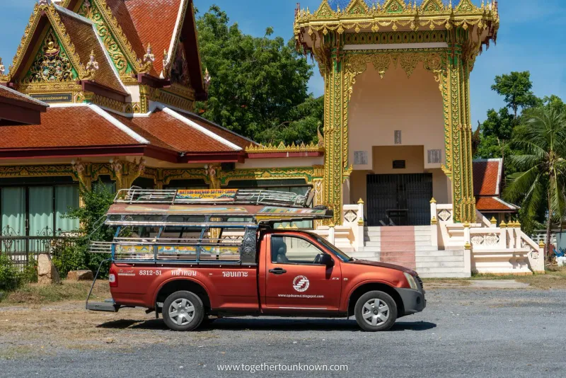 Pickup rosso songthaew con portapacchi parcheggiato davanti a un tempio thailandese a Koh Samui