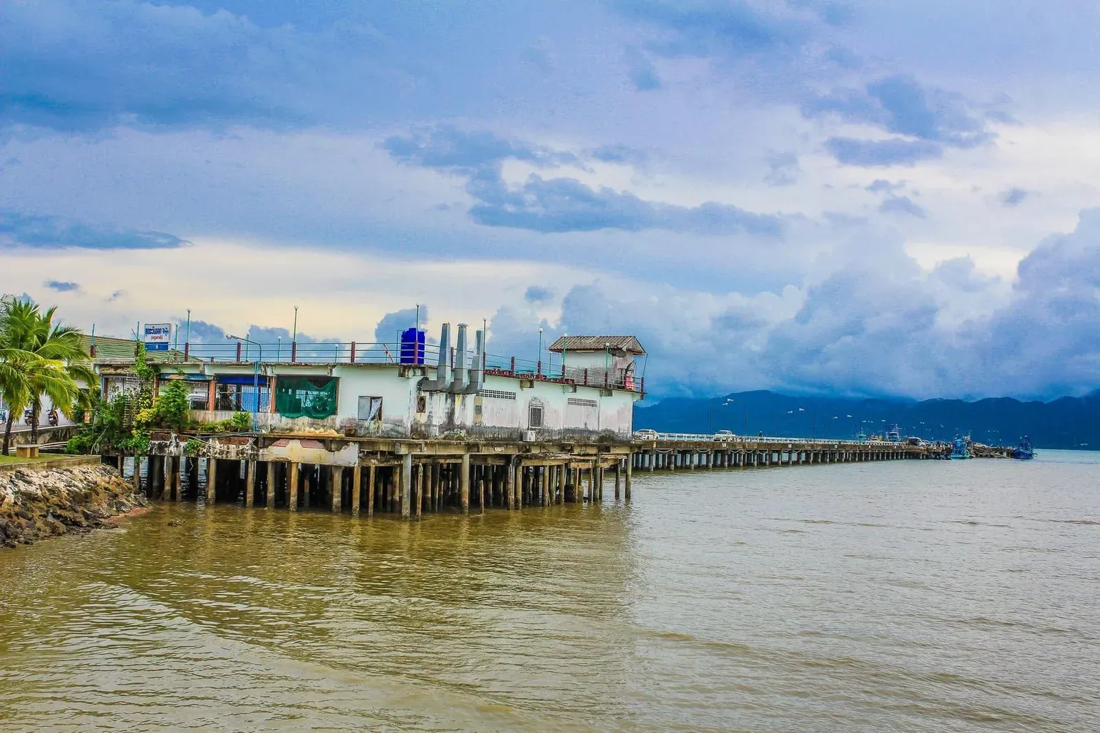 Long concrete pier extending into the sea near Surat Thani with a ferry terminal building