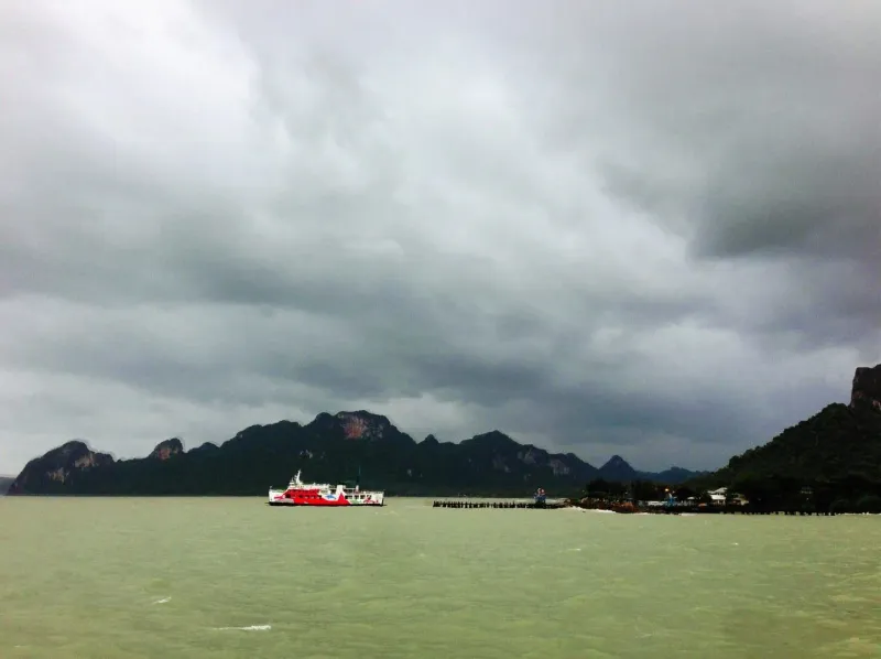 Traghetto che attraversa acque mosse nel Golfo di Thailandia sotto un cielo nuvoloso