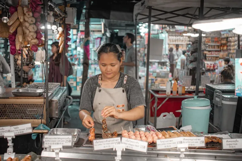 Vendor grilling skewers, a dish style covered in Koh Samui cooking class menus