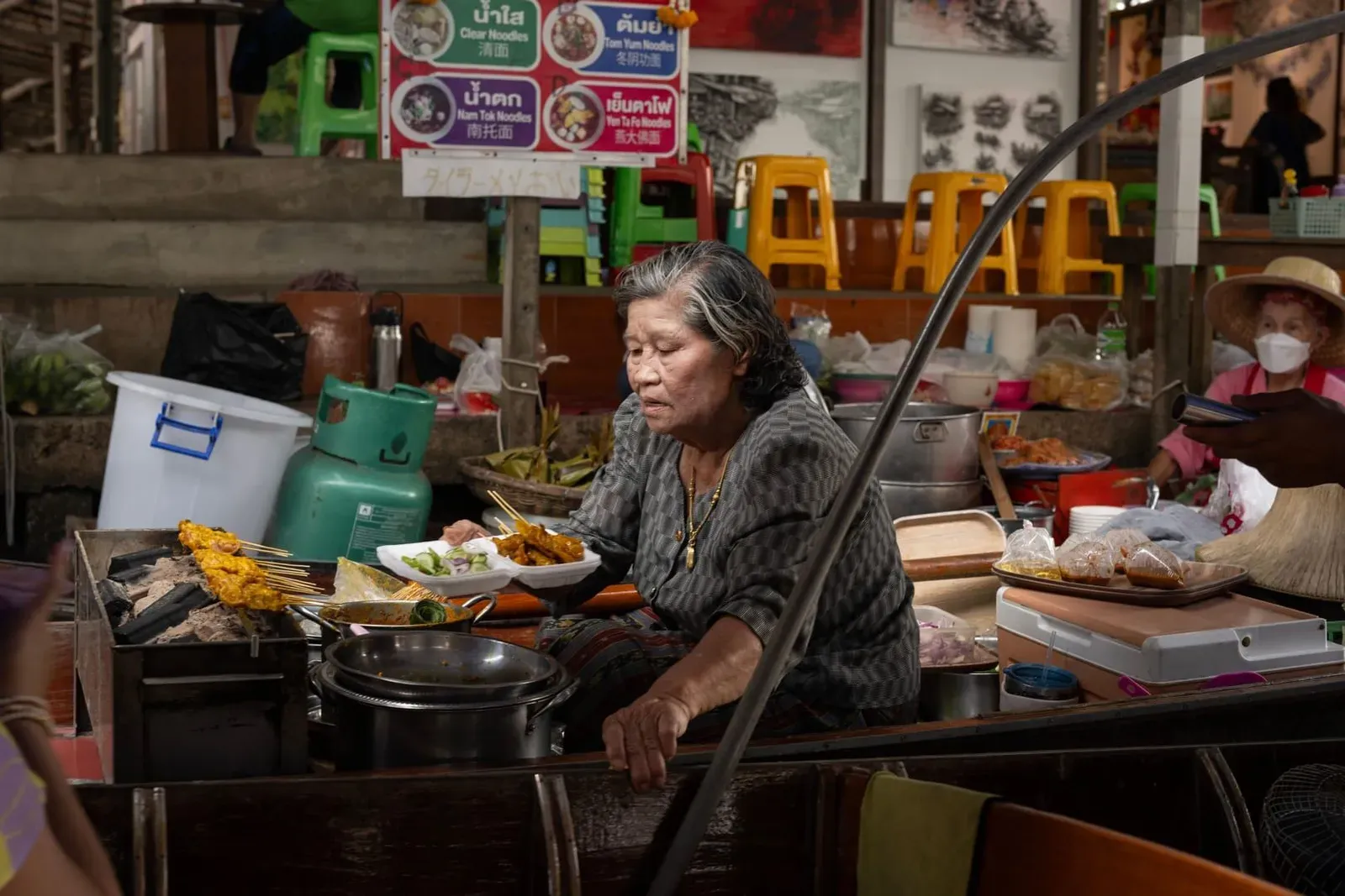 Thai cook preparing a dish at a market-style kitchen counter near Koh Samui