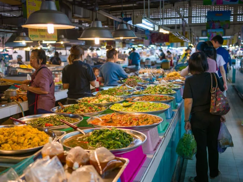 Bustling Thai market scene representing ingredient sourcing for cooking classes