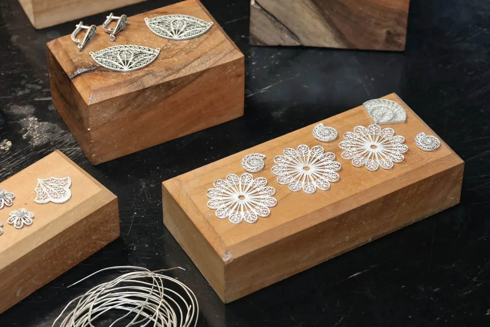 Silver filigree jewellery pieces displayed on wooden blocks