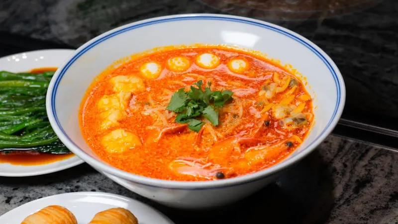 Bowl of spicy southern Thai style soup with seafood and fresh herbs