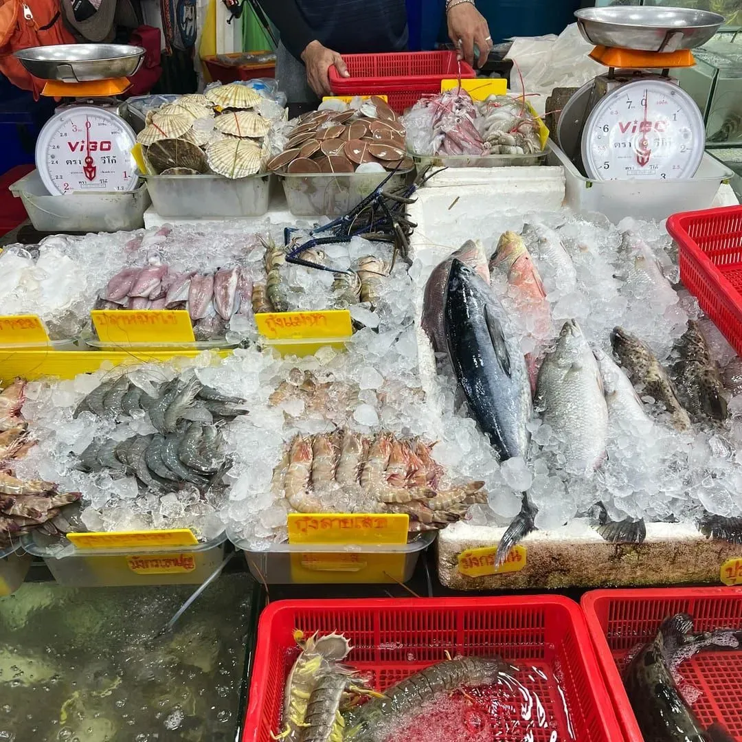 Fresh fish and shellfish displayed on ice at a Thai seafood market stall similar to Hua Thanon