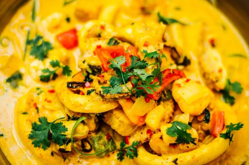 Close-up of a rich southern Thai seafood curry garnished with fresh herbs
