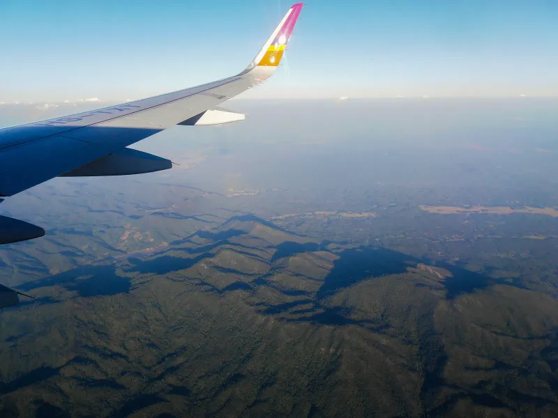 Ala di un aereo di linea sopra colline boscose vista dal finestrino su un volo nazionale in Thailandia