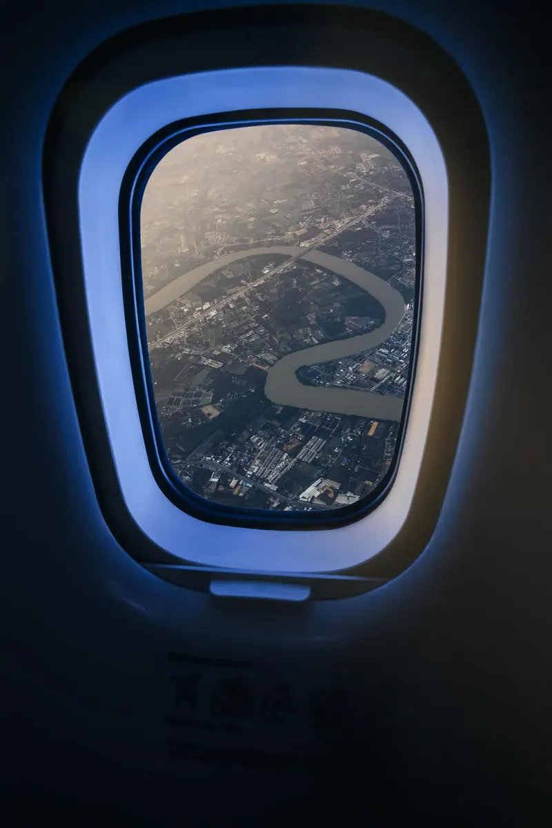 Fiume che serpeggia tra campi e sobborghi visto dal finestrino di un aereo di linea sulla Thailandia